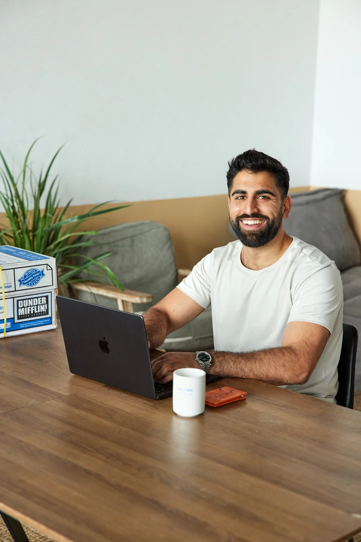 Nik smiling at his desk with a laptop